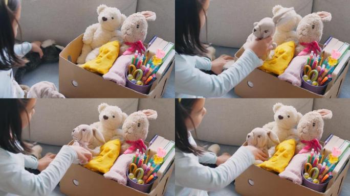 混合亚洲青年志愿者女孩整理一盒二手玩具，衣服，书籍和文具用于捐赠，快乐慈善，亚洲社区
