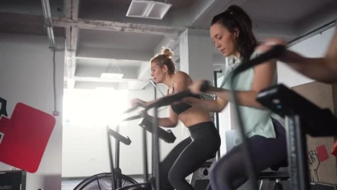 一群活跃而健康的白人女运动员，在固定的骑行器上锻炼