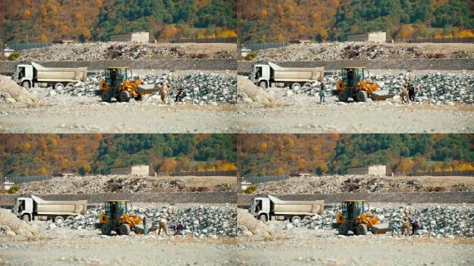 一组三人将河边的石头装入挖掘机的铲斗中。