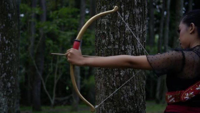 一名妇女从丛林中的弓箭中释放出强大的箭