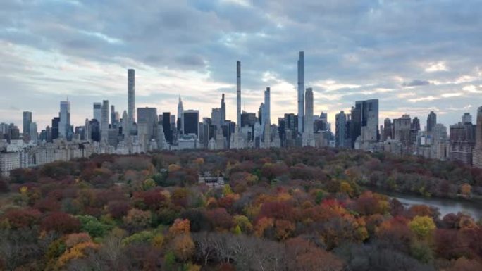 在多云的天空下，市区高层建筑的全景。中央公园里的彩树。美国纽约市曼哈顿