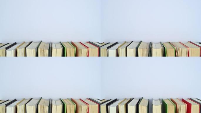 一堆不同颜色的精装书在书架上移动，有空的文字空间。停止运动平铺