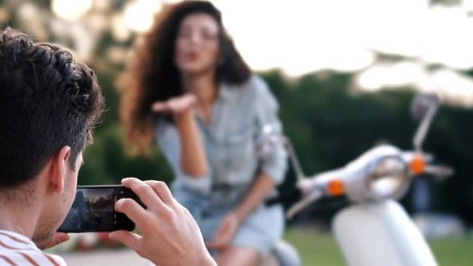 男子用手机在滑板车户外拍女友照片