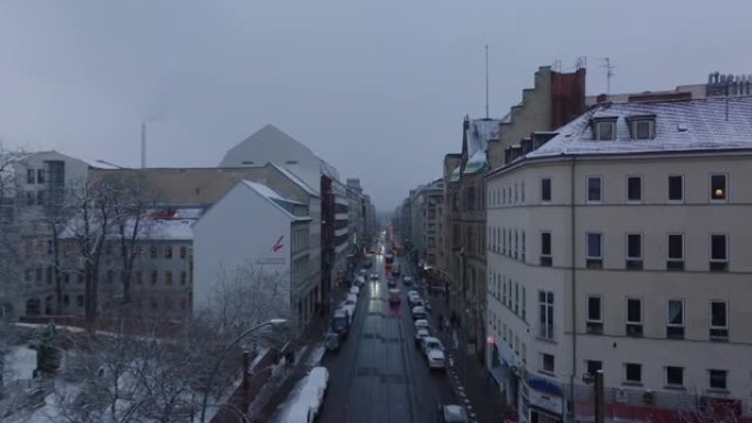 黄昏时在冬季城市街道上行驶的汽车的前瞻性跟踪。沿着公寓楼飞。德国柏林