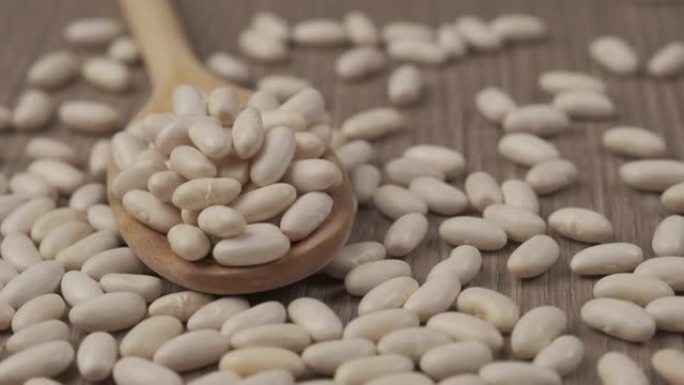 木勺旋转的白色干豆豆类。素食素食成分，地中海饮食