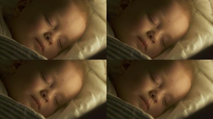 婴儿襁褓躺在婴儿床里，9个月的男婴睡在夜灯下。9个月大的高加索儿童特写镜头。