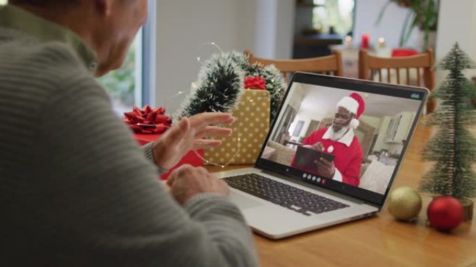 白人高级男子在笔记本电脑上与屏幕上的非洲裔美国圣诞老人进行圣诞节视频通话