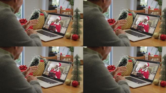 白人高级男子在笔记本电脑上与屏幕上的非洲裔美国圣诞老人进行圣诞节视频通话