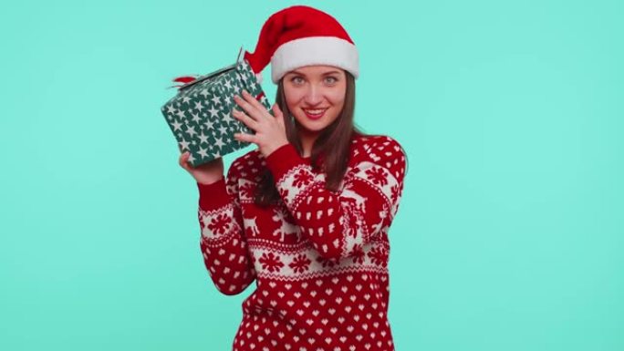 有趣的女孩穿着圣诞假期毛衣收到礼物，对礼品盒里面有什么感兴趣