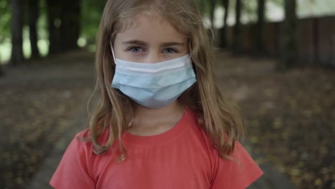 大流行，城市街道上戴着防护面具的小女孩的肖像。面对儿童戴口罩，保护他们免受病毒空气污染。流行病冠状病