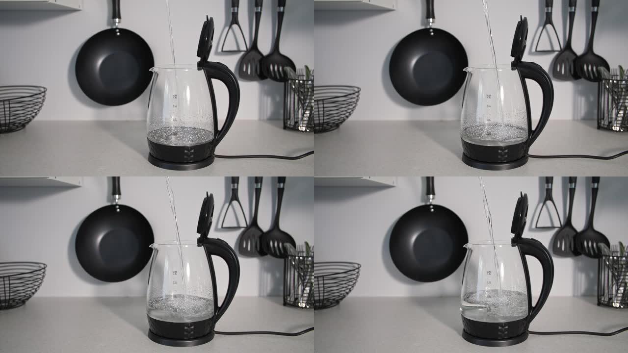 家用，干净的凉水倒入透明的电热水壶中，用于煮沸厨房用具的背景