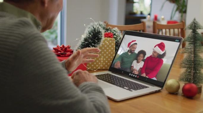 白人高级男子在屏幕上与非裔美国人家庭在笔记本电脑上进行圣诞节视频通话