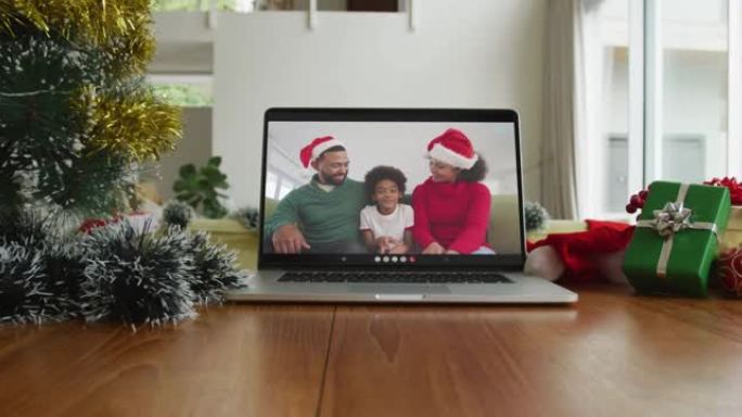 微笑的非裔美国人家庭戴着圣诞老人的帽子在笔记本电脑上的圣诞节视频通话中