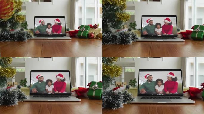 微笑的非裔美国人家庭戴着圣诞老人的帽子在笔记本电脑上的圣诞节视频通话中