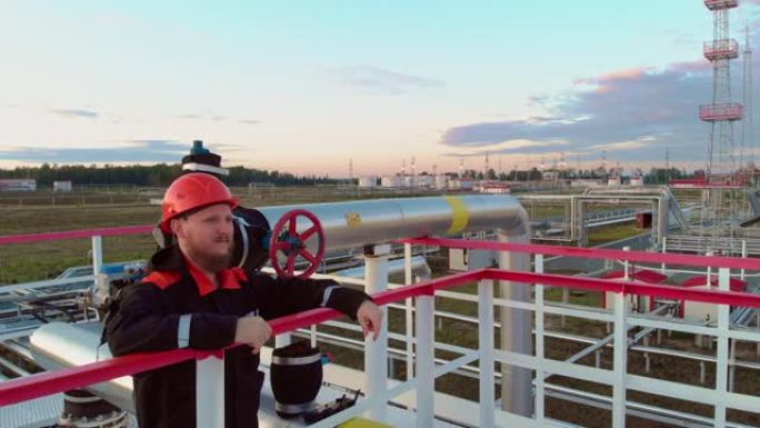 石油和天然气行业，工程师在对讲机上传输读数。戴着头盔的工人站在管道和配件附近的压力容器上。用于甲烷气