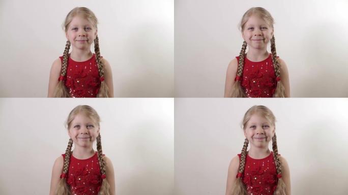 一个漂亮的小女孩5岁的肖像。一个穿着优雅红色连衣裙的孩子。扎着辫子的女孩看起来笔直，面带微笑。节日概