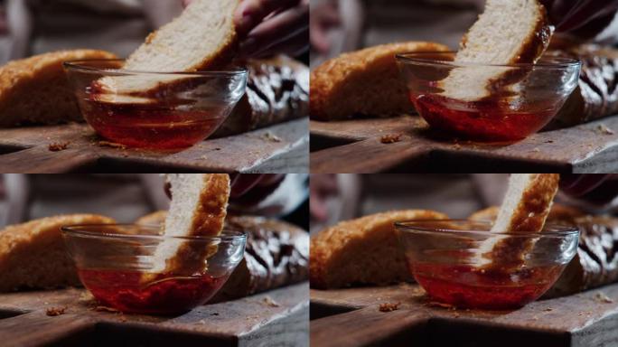 人手将一片意大利脆皮面包浸入番茄油中