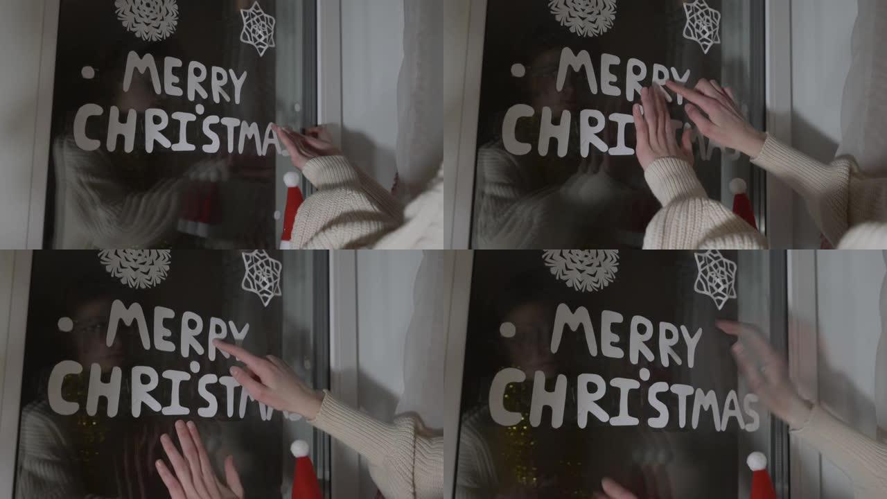 女孩手里拿着纸质信件，在窗户上粘贴圣诞快乐的文字