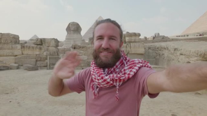 年轻人旅行在吉萨大金字塔前自拍。男性在埃及开罗与金字塔和狮身人面像一起自拍