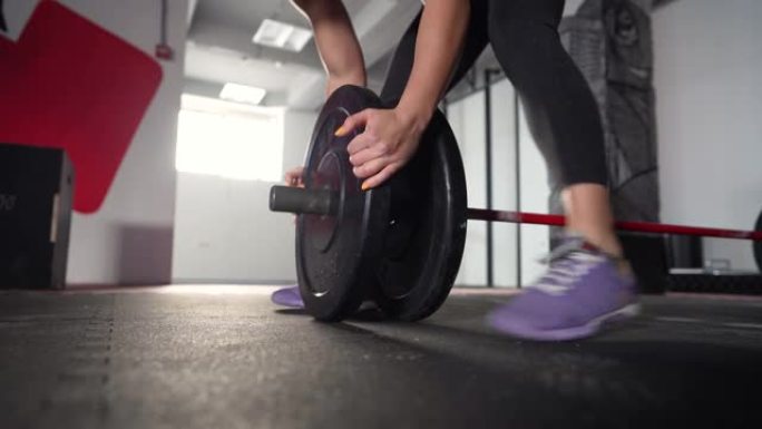 无法识别的高加索女运动员，在现代健身房锻炼时调整杠铃上的重量
