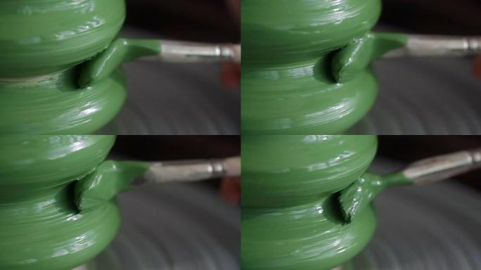 特写镜头: 波特用大刷子在波特的轮子上画一个水罐，来自陶器车间的视频，陶艺家以慢动作制作陶瓷，4k 