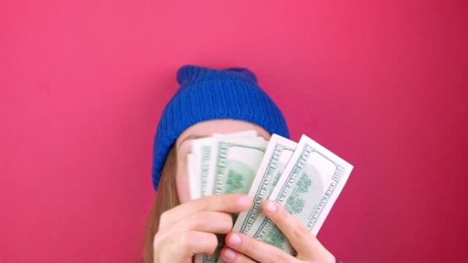 女人拿着美元钞票粉红色背景。女孩计数现金美国100美元纸币。赚取储蓄美国货币兑换财富概念。在线赌场赢