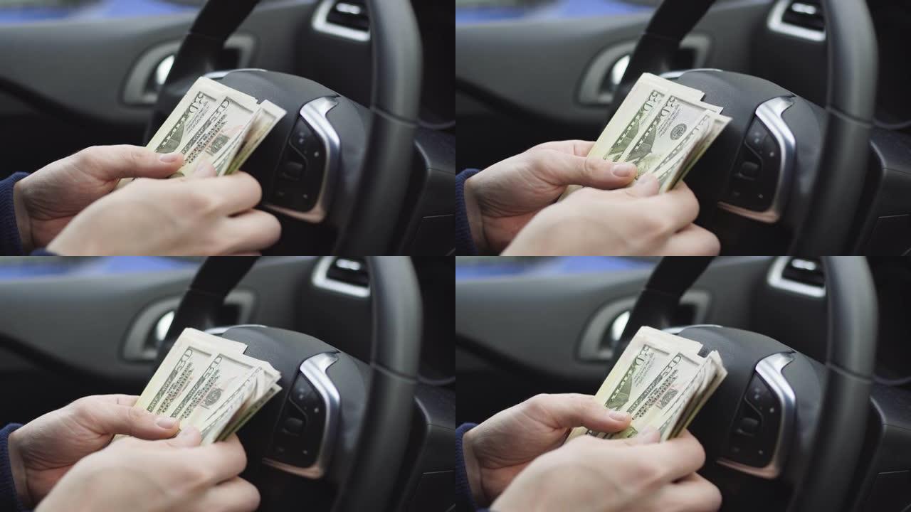 男子坐在汽车上数美元钞票，关闭男性手数钱现金。收益或贿赂、保险或信贷、投资的概念