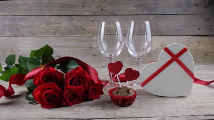 情人节。两杯香槟，红玫瑰，木制背景上的心形盒子。香槟倒了。