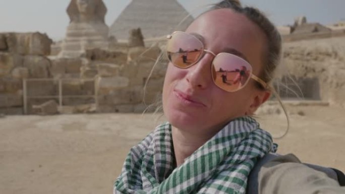 慢动作: 年轻的单人旅行女子在吉萨大金字塔前自拍。女性在埃及开罗与金字塔和狮身人面像一起自拍