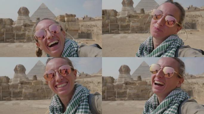 慢动作: 年轻的单人旅行女子在吉萨大金字塔前自拍。女性在埃及开罗与金字塔和狮身人面像一起自拍