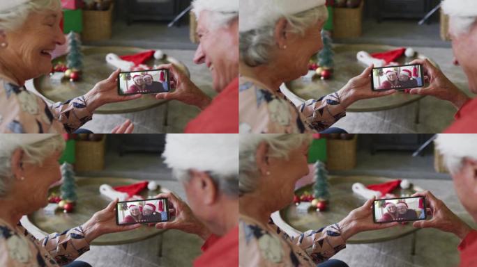 微笑的高加索高级夫妇使用智能手机与屏幕上的夫妇进行圣诞节视频通话