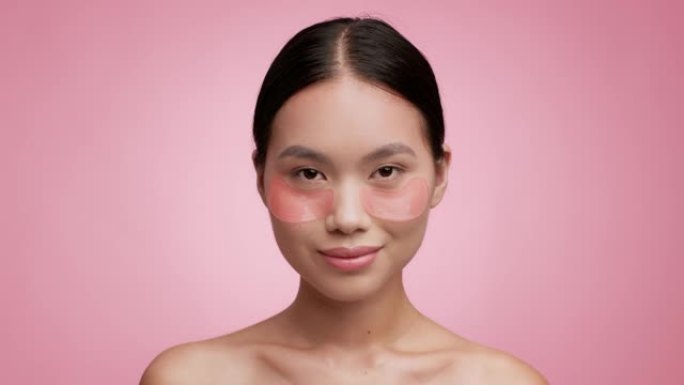 亚洲女性应用眼底贴剂保湿脸，粉色背景