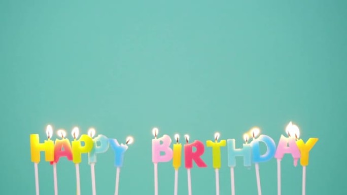 生日快乐概念由在蓝色或绿松石背景上燃烧五颜六色的蜡烛制成。慢动作全高清视频。祝你生日快乐。