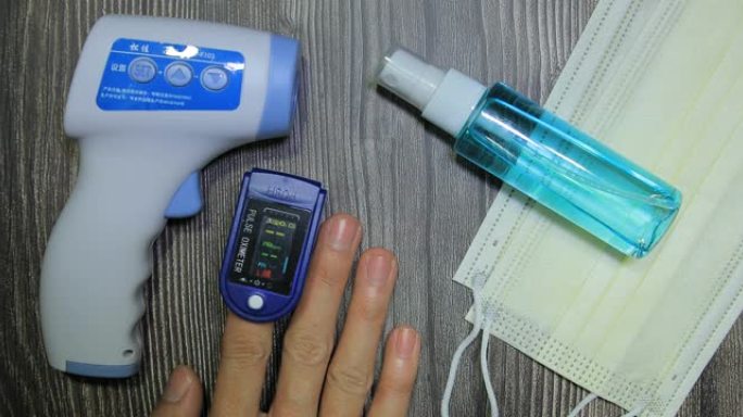人类男性手脉搏血氧仪用于测量脉搏率和氧气水平木桌背景纹理与复制空间。顶视图。医疗概念防护医用口罩，电