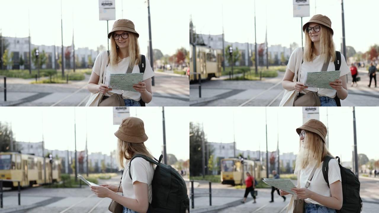 年轻的旅游女子背着背包在地图上寻找正确的方向，在户外的电车站等待公共交通工具。去欧洲旅行