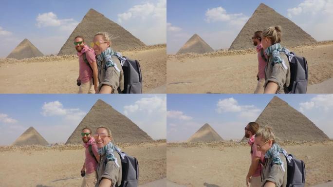 年轻夫妇使用自拍杆在埃及旅行，参观开罗的大金字塔。