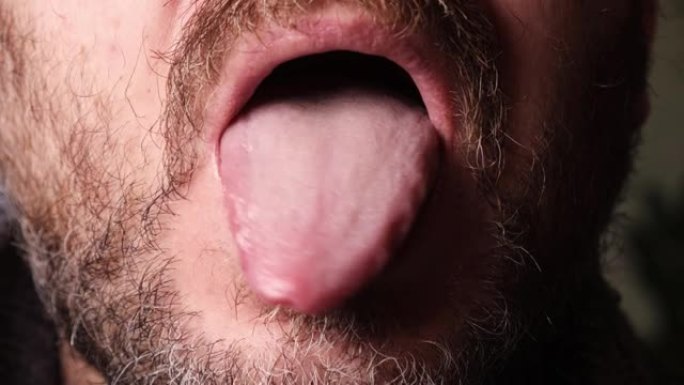 没有刮胡子的人张开嘴，伸出舌头。
