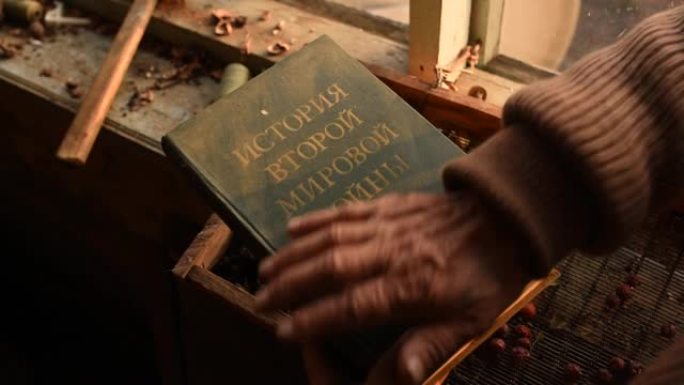 题词:第二次世界大战历史。一位老人拿着掸去灰尘的封面苏联历史书