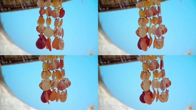 在热带海滩上的夏季brezee上挥舞着蓝色天空 (风铃) 的弦贝壳装饰的特写镜头