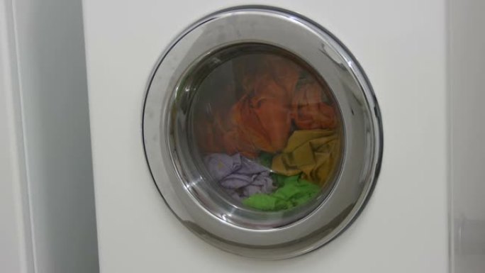 多色衣物洗衣房在白色洗衣机中洗涤。