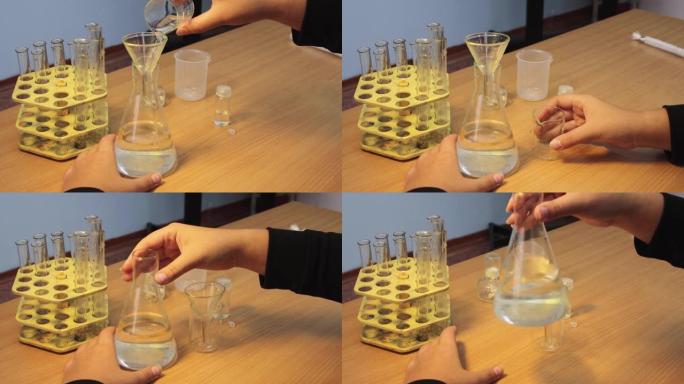 瞳孔的手近距离将化学试剂从玻璃杯中倒入烧瓶中。