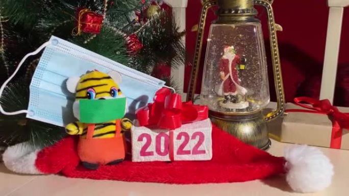 象征2022年新年的老虎带着防护面具，圣诞灯带着圣诞老人和新年树。冠状病毒大流行期间的安全假日庆祝概