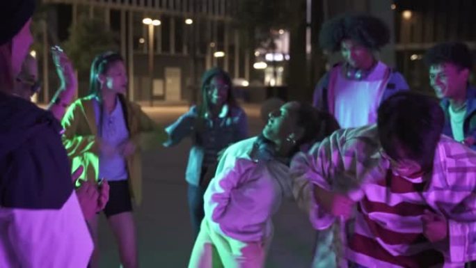 一群时髦的年轻多样化的青少年朋友晚上在城市的音乐街派对上跳舞很开心