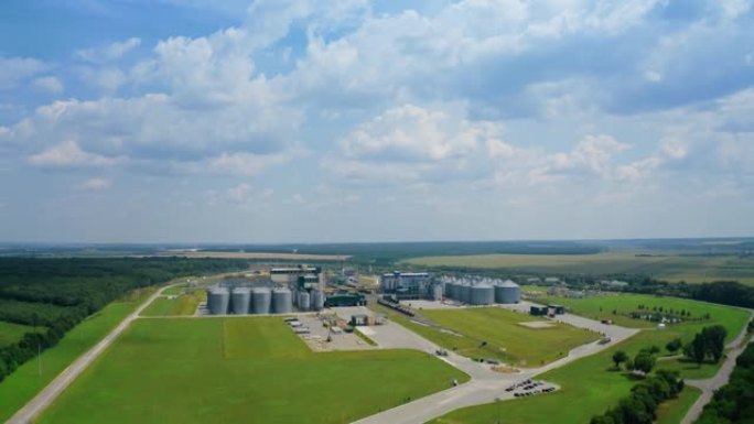 绿地上的现代工业厂房。夏季自然中带有谷物升降机的农业工厂。全景。从空中看。