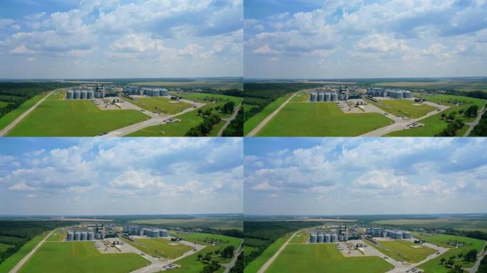 绿地上的现代工业厂房。夏季自然中带有谷物升降机的农业工厂。全景。从空中看。