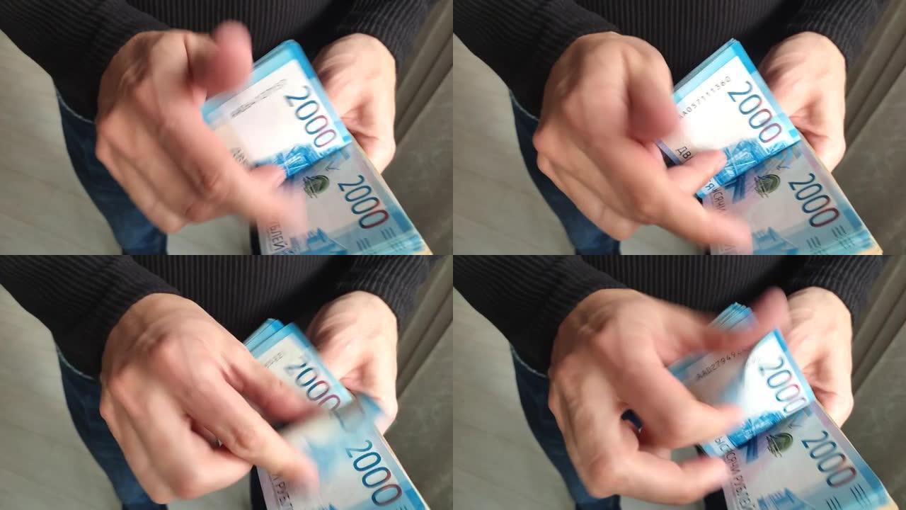 一个人手里拿着一大笔钱。一个男人的手的特写镜头数了一捆2000俄罗斯卢布的钞票