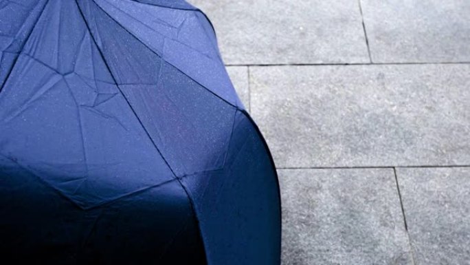 雨天用水滴收上雨伞。从上到下倾斜镜头。主题在左边。
