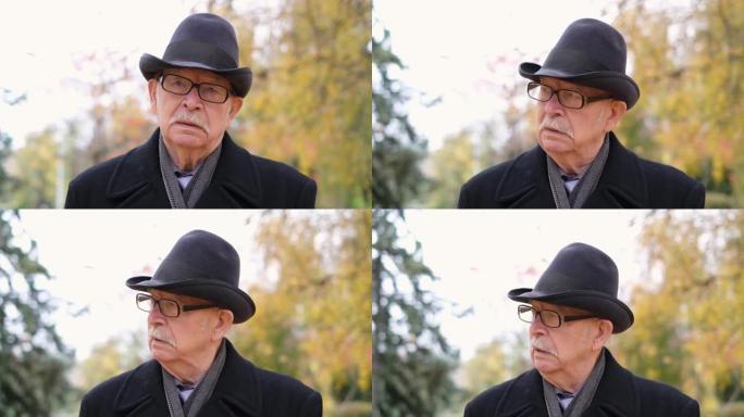 公园里孤独的爷爷，穿着黑色外套和黑色帽子。
