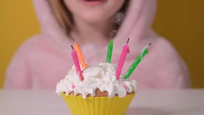 穿着粉色工作服的快乐小女孩在派对上吹出五支生日蛋糕上的蜡烛。特写女孩的脸。慢动作生日快乐视频横幅