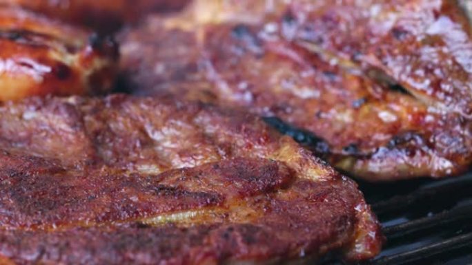 在烤架上特写两片肉。一片肉正在转动。